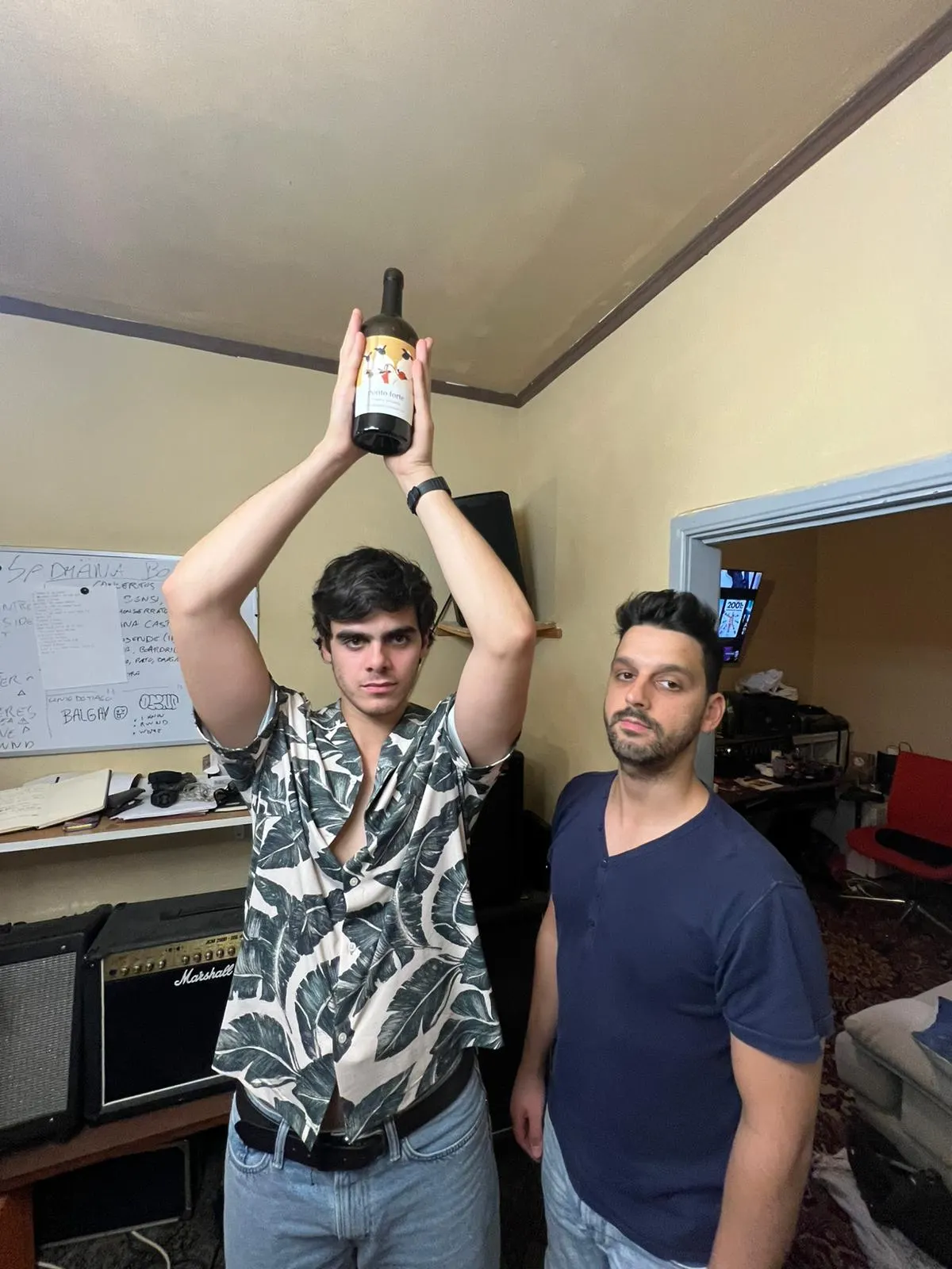 Sadhäna band members holding a giant bottle overhead in the rehearsal room
