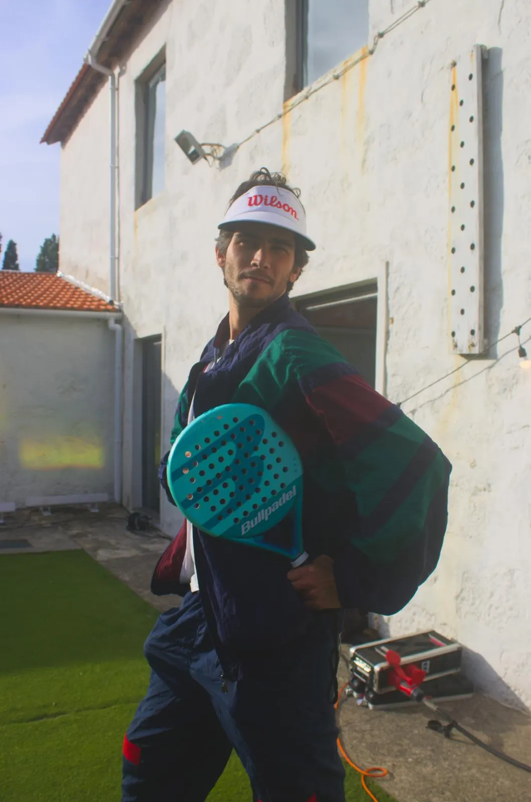 Sadhäna band member posing with a padel racket outside a house