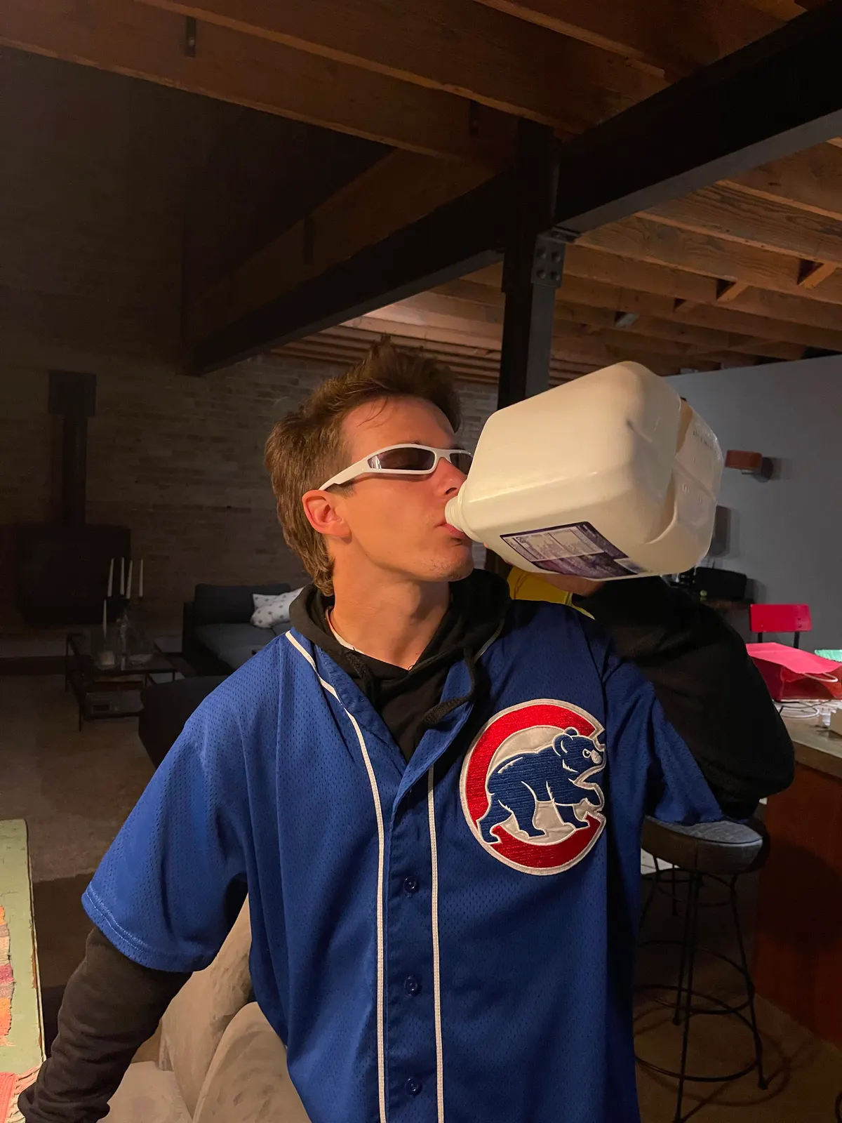 Sadhäna band member drinking from a large jug while wearing a baseball jersey